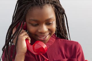 Image of child holding the red handset of a corded phone